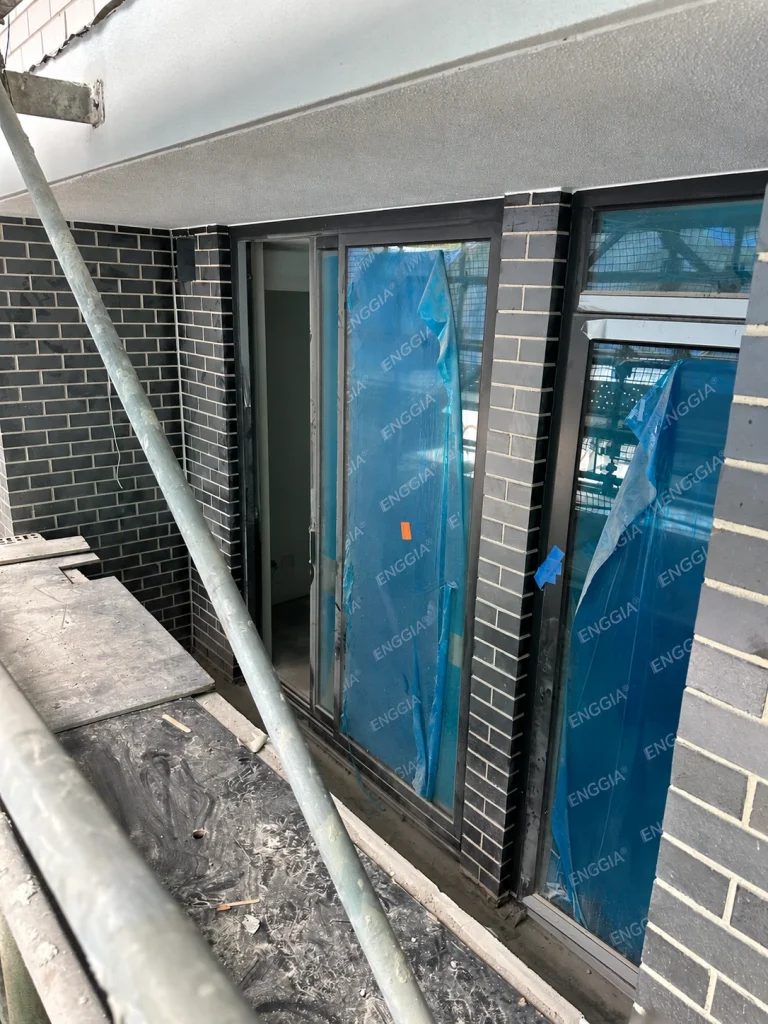 Dark-framed glazed opening beside brickwork